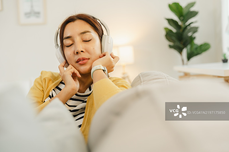 女性在家中放松，戴着耳机，享受音乐。提升您的听觉体验，享受舒适的氛围和顶级音质。图片素材