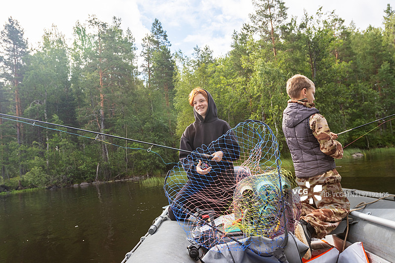 青少年在他们的摩托艇上练习钓鱼技巧。家庭在偏僻的森林湖泊中增进感情。图片素材