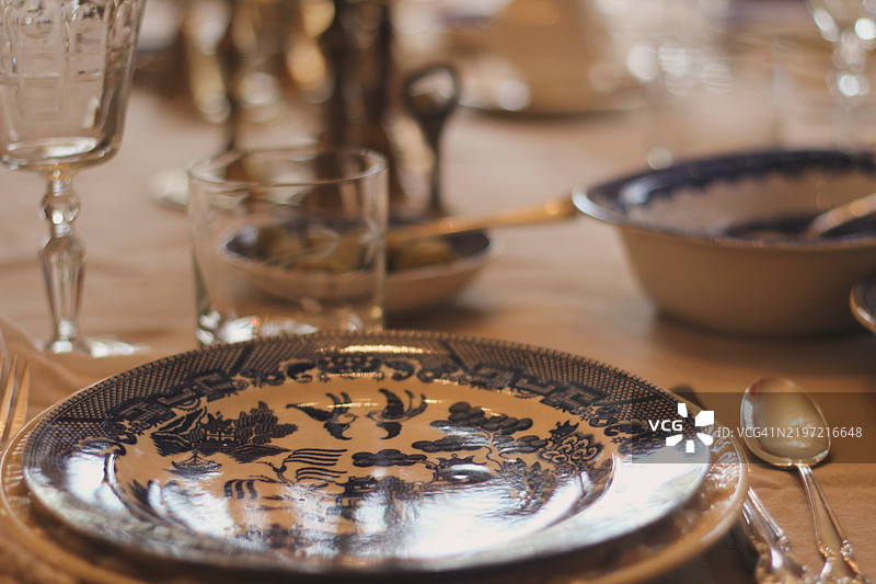 节日餐桌上摆放着收集的复古餐具、银器和烛台。古董蓝白瓷器搭配二手的纯银餐具。各种黄铜烛台装饰着餐桌。庆祝活动和节日餐宴。图片素材
