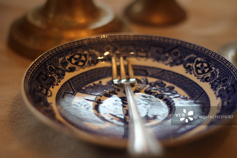 节日餐桌上摆放着收集的复古餐具和银器。古董蓝白瓷器搭配二手的纯银餐具。在餐厅的餐桌上庆祝节日和享用美餐。图片素材