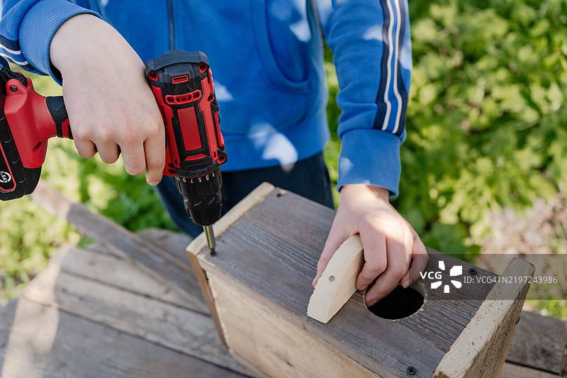 一个男孩的手在春天制作鸟屋图片素材