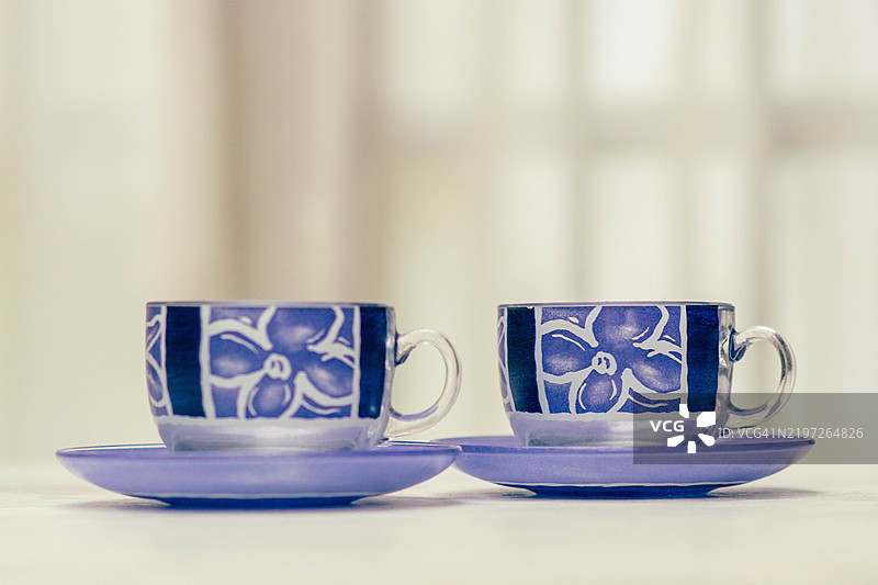 两个空的紫色茶杯，带有花卉图案，放在茶托上图片素材