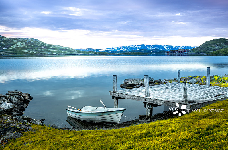 一只小船准备在湖上出发。夏天的山上覆盖着雪，景色令人叹为观止。图片素材