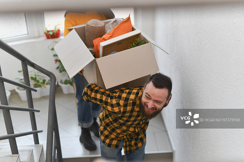 微笑的男性在搬家日与女性朋友一起开心地背着重箱子图片素材
