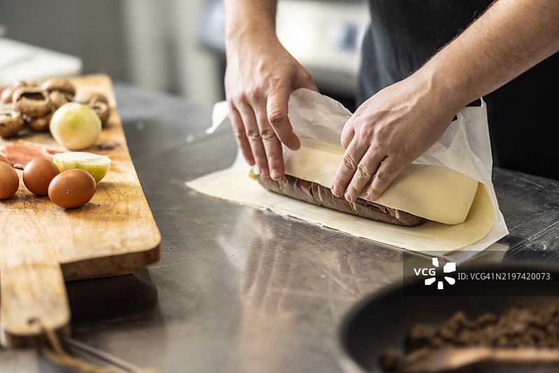 准备威灵顿牛肉的最后一步之一。厨师将准备好的肉包裹在酥皮中。图片素材