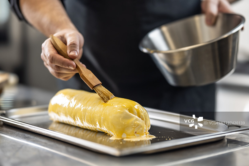 准备威灵顿牛肉的最后步骤之一。厨师用打散的鸡蛋刷在酥皮上。图片素材