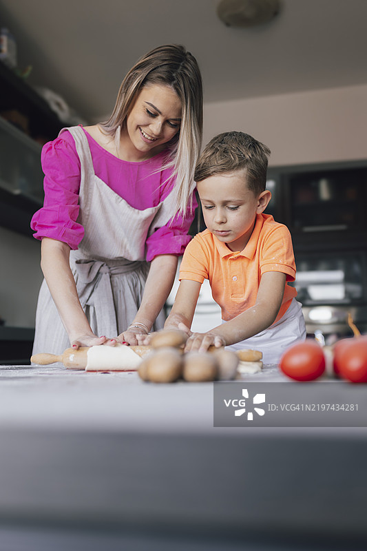 快乐的母亲和儿子在现代厨房一起制作面团图片素材