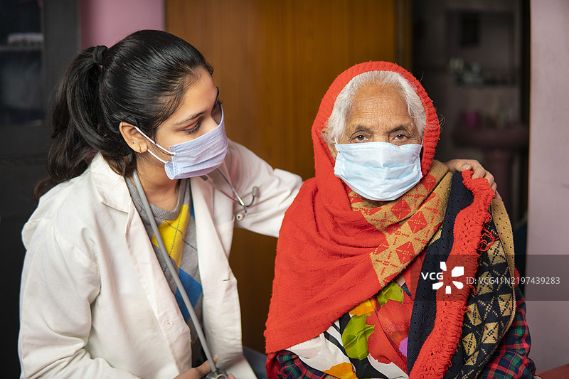 印度女性医生在家中安慰并给予老年女性患者心理支持。图片素材