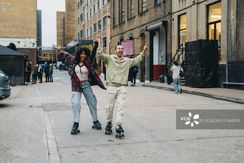 快乐的情侣在伦敦滑旱冰并举起双臂图片素材