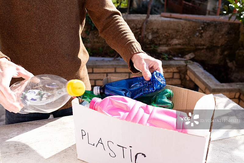 男性手将塑料瓶放入回收箱中图片素材