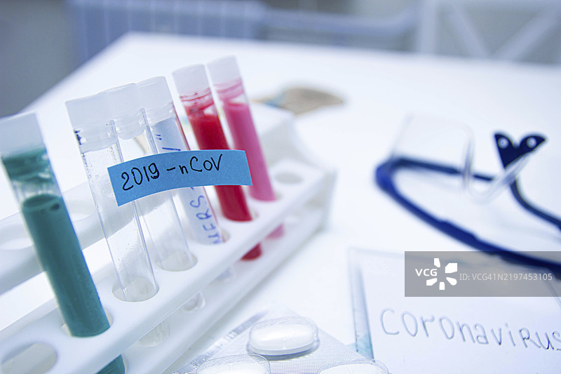 桌子上放着试管和蓝色标签“2019-nCoV”，旁边有医疗物品和听诊器。图片素材