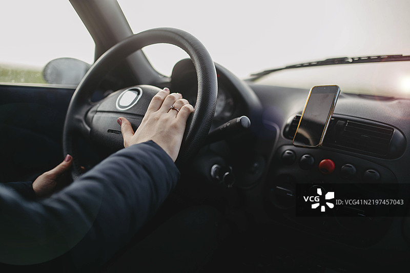 汽车仪表盘视图，手握方向盘，手机放在支架上图片素材