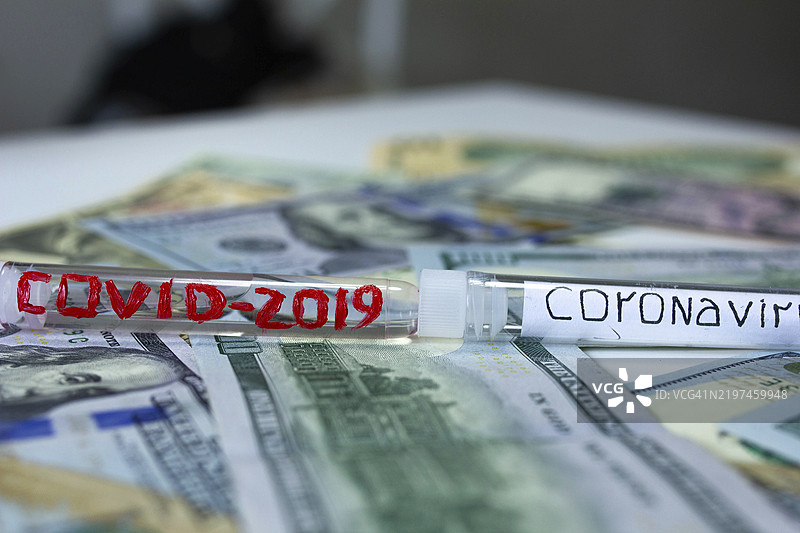 COVID-2019和冠状病毒试管放在钱上，强调疫情对经济的影响图片素材