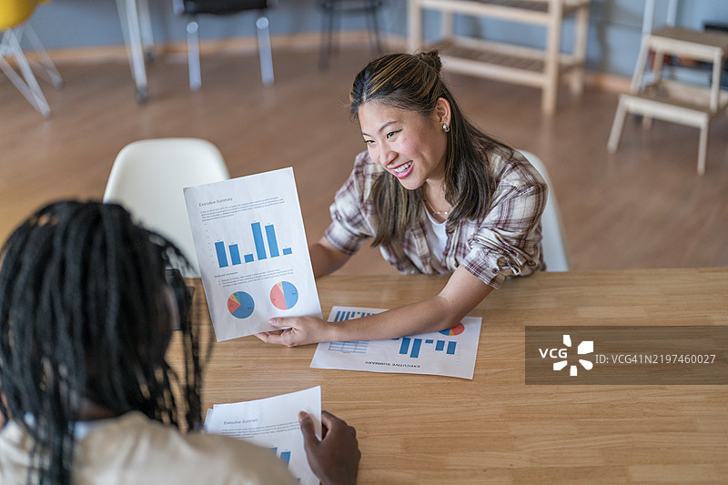 年轻女商人在办公室会议室向同事解释统计数据图片素材