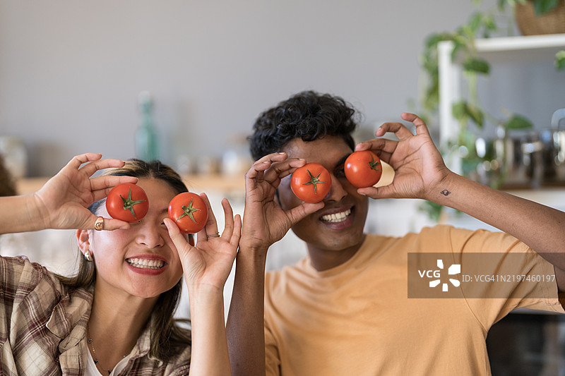 年轻情侣在厨房里玩番茄，享受乐趣图片素材