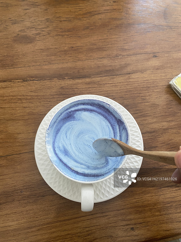 从上方直接拍摄的人手握勺子和咖啡杯放在桌子上图片素材