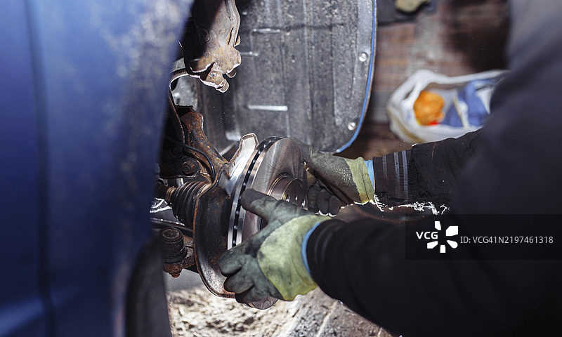 机械师的手正在修理汽车刹车盘，维护工作进行中图片素材