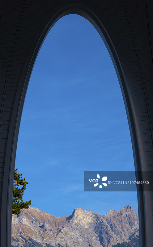 瑞士圣加仑巴德拉加兹阳光明媚的一天，漂亮的拱形窗户、山脉、树枝和阳光照耀的天空图片素材