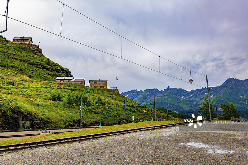 美丽的火车站与铁路轨道，背景是阿尔卑斯山的阿尔普格鲁姆，位于瑞士伯尼纳的波斯基亚沃，夏日多云的景色。图片素材