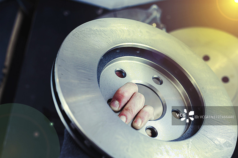 手握金属刹车盘，阳光洒在上面图片素材