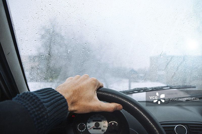 透过雾蒙蒙的挡风玻璃看着握着方向盘的手图片素材