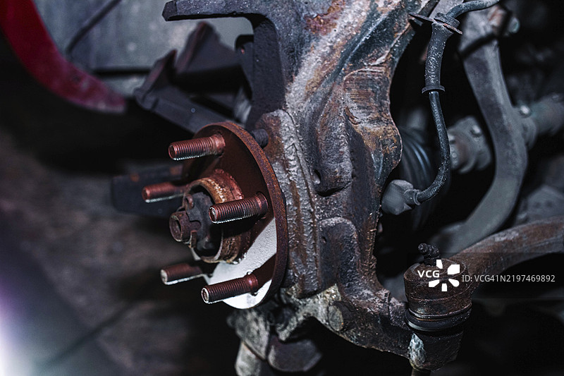 生锈的车辆刹车盘支架，未安装刹车盘，置于昏暗的车间环境中图片素材