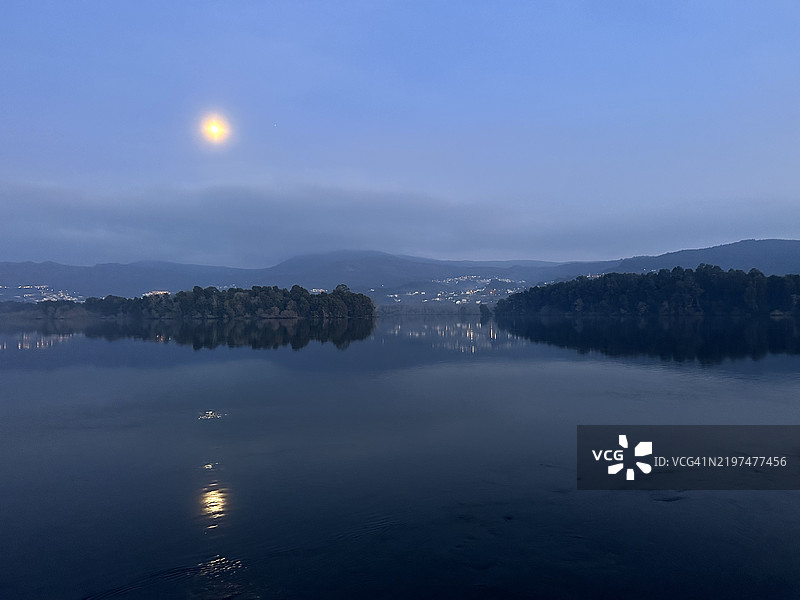 满月倒映在西班牙加利西亚O Rosal附近Eiras的米尼奥河平静水面上图片素材