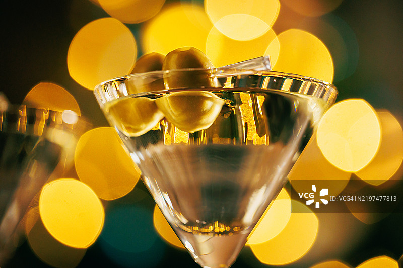 特写的马提尼酒与橄榄和温暖的节日灯光图片素材