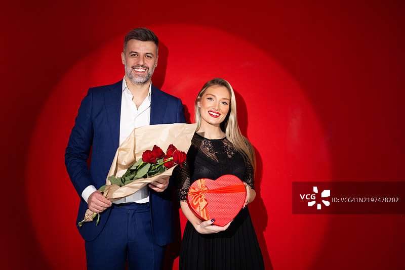 甜蜜的工作室肖像，丈夫向妻子赠送玫瑰和礼物图片素材