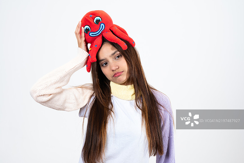 年轻女子头上戴着章鱼玩具，显得伤心和无聊图片素材