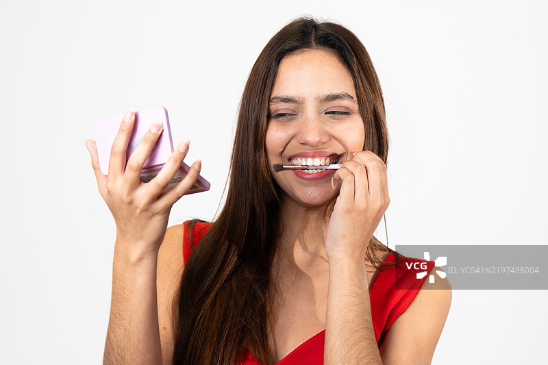 年轻的拉丁裔女性微笑着用刷子和调色板化妆图片素材