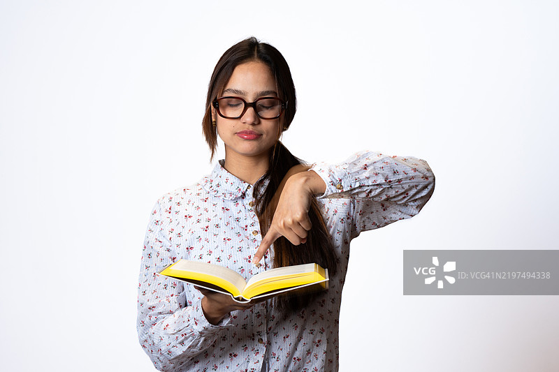 年轻女性在白色背景下阅读并指着一本书图片素材