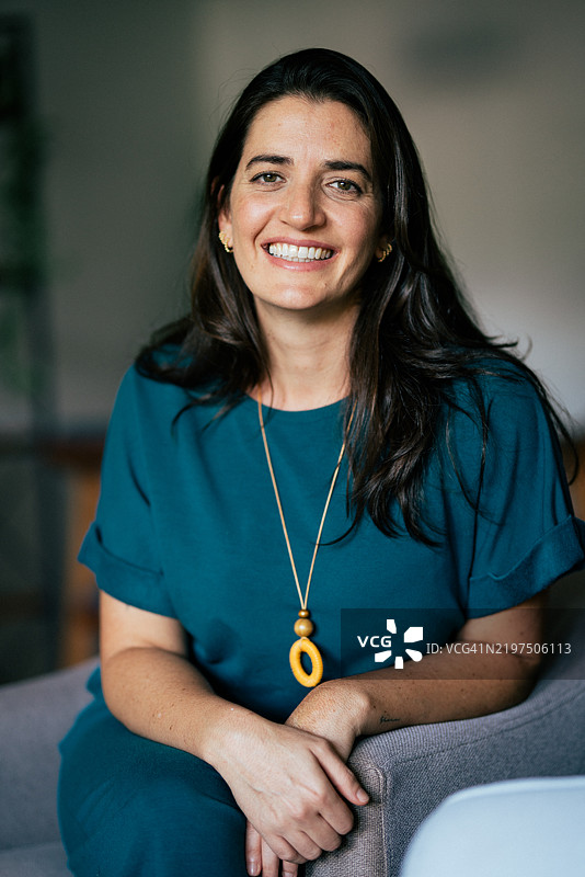 年轻女性坐在客厅的扶手椅上，正面朝向镜头。图片素材