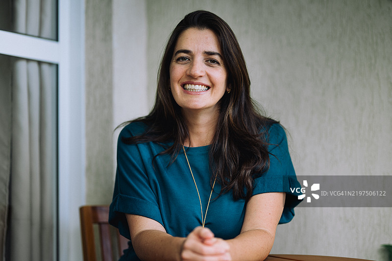 微笑的年轻女性在阳台上半身朝向镜头。图片素材