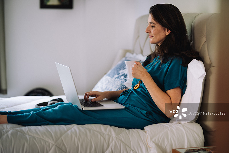 侧面视角的女人坐在卧室的床上图片素材