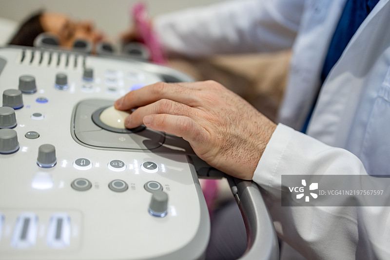 男性医生为成熟的女性患者进行颈部超声检查图片素材