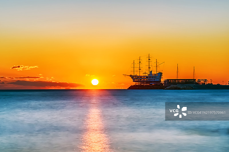 日出时分，海面上有一座船形建筑的码头图片素材
