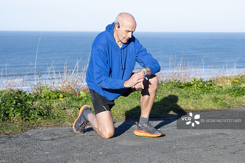 成熟男性（60-69岁）在慢跑时查看设备图片素材