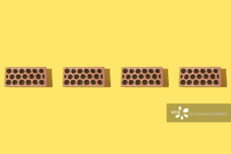 红色砖瓦的排列，整齐地放在黄色背景上。建筑，投资，工作，装修，房屋，抵押贷款图片素材