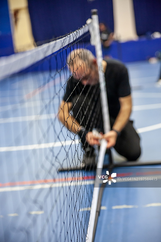 老年男性皮克球运动员正在硬地场上准备便携式网子，静态运动画面图片素材