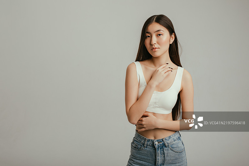 时尚的亚洲女性在工作室中穿着休闲牛仔裤和白色上衣摆姿势图片素材