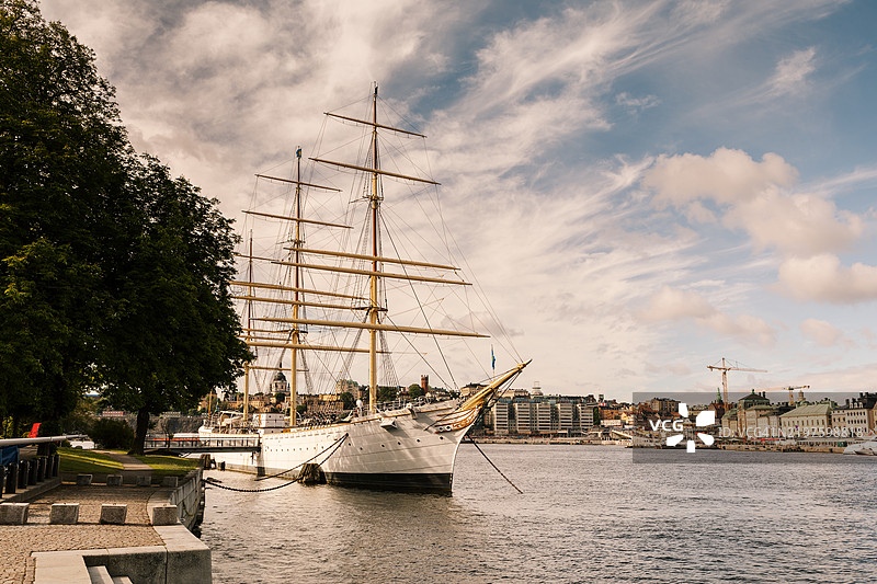 一艘古老的帆船停泊在大城市中心的一个岛屿上。图片素材