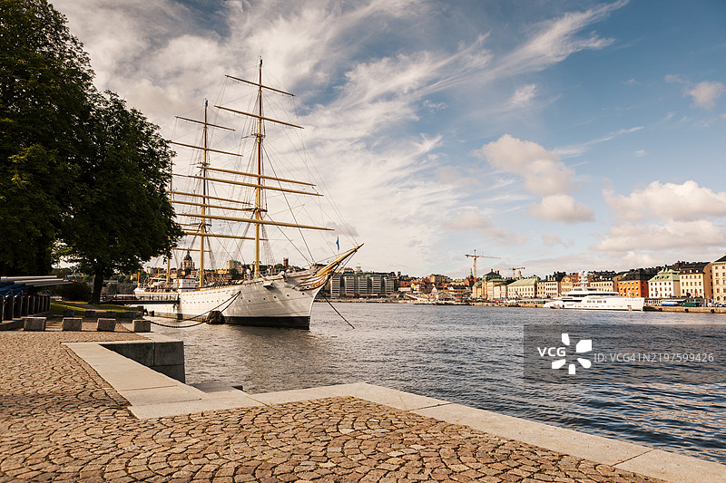 一艘古老的帆船停泊在大城市中心的一个岛屿上。图片素材