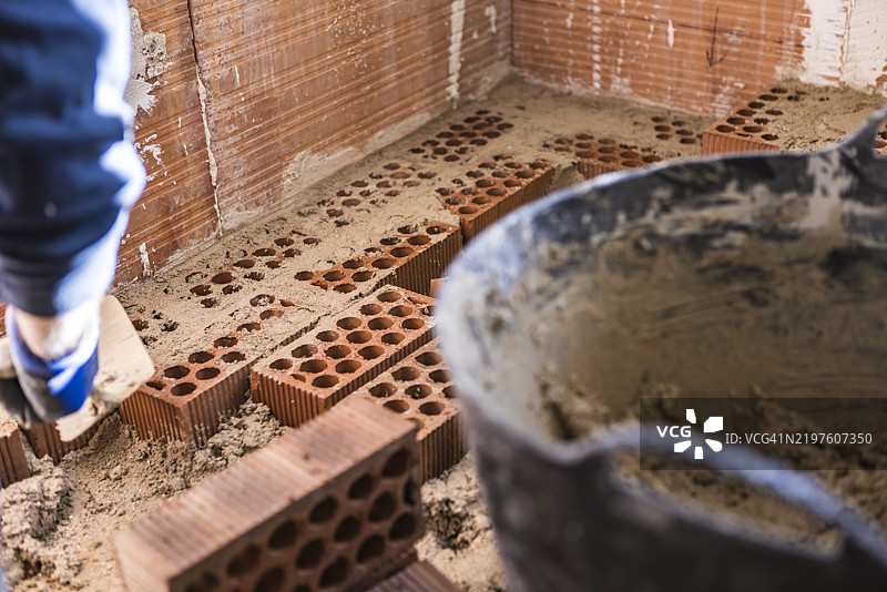 砖工在建筑工地上用砂浆砌筑空心砖。工作、装修、投资、房屋、修缮、砖工。图片素材