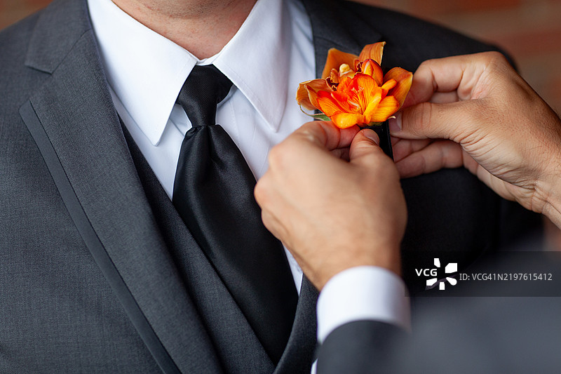 男子在西装外套上别花束胸花图片素材