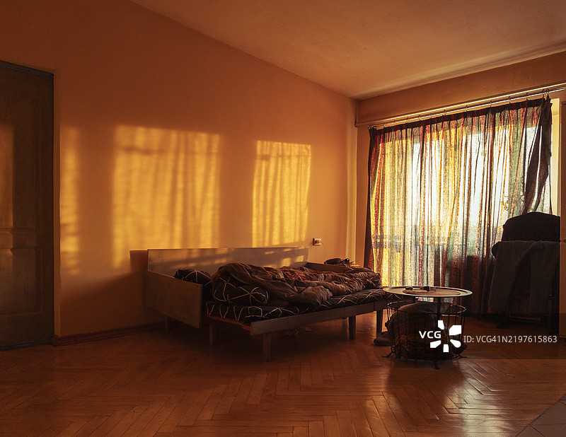 温暖的下午阳光洒进一个舒适的房间，在窗户附近的墙壁和家具上投下金色的阴影。图片素材