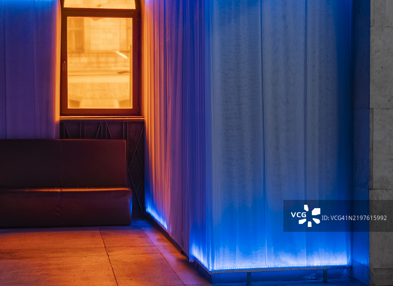 五光十色的灯光和舒适的角落在现代城市休息室的夜晚邀请人们放松。图片素材