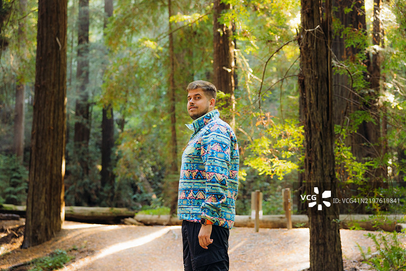 阳光下在红木森林中散步的快乐男子侧面视图图片素材