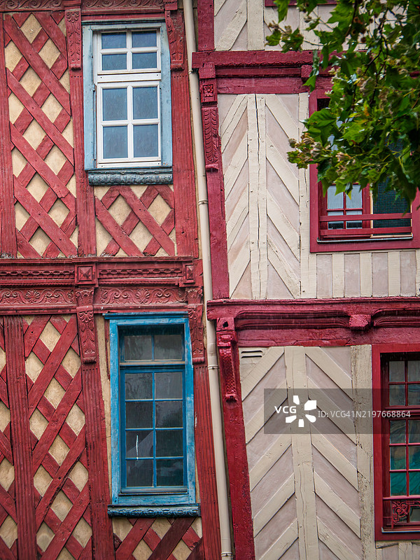 勒讷著名广场香普雅克的倾斜房屋红色和米色的半木结构外立面的特写,配有古老的蓝色和红色窗框,位于伊勒-维莱讷 - 布列塔尼 - 法国西部。图片素材