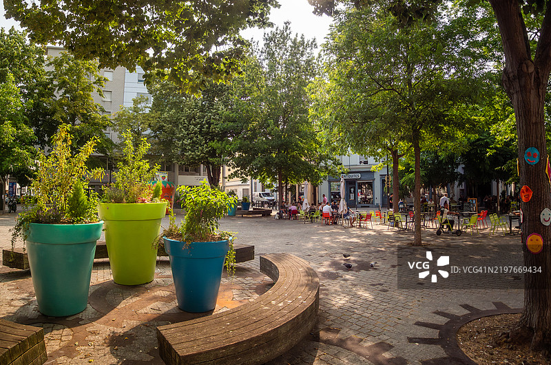 穆尔豪斯市中心的和平广场宽角度视图,这是一座大型的鹅卵石步行广场,周围种满了树木和咖啡馆露台,人们在享用饮品,夏季装饰点缀其间,位于阿尔萨斯的上莱茵省,东法兰西。图片素材